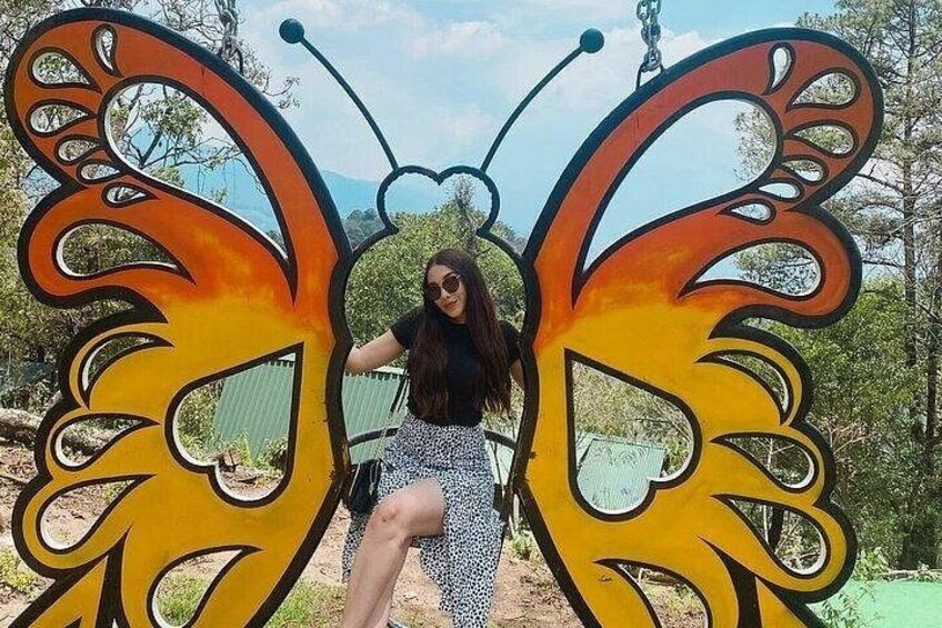 A person sitting in front of a large butterfly sculpture. 2