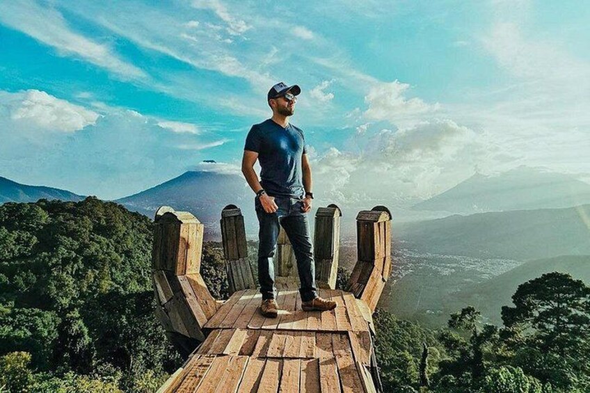 A person standing on a wooden platform with a mountainous landscape in the background. 4