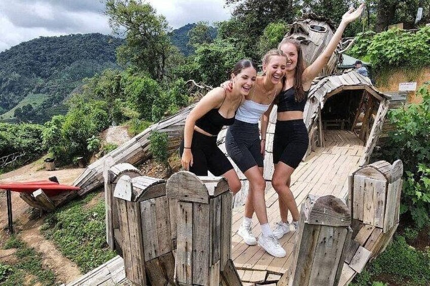 Three people on a wooden bridge with a mountainous landscape in the background. 3