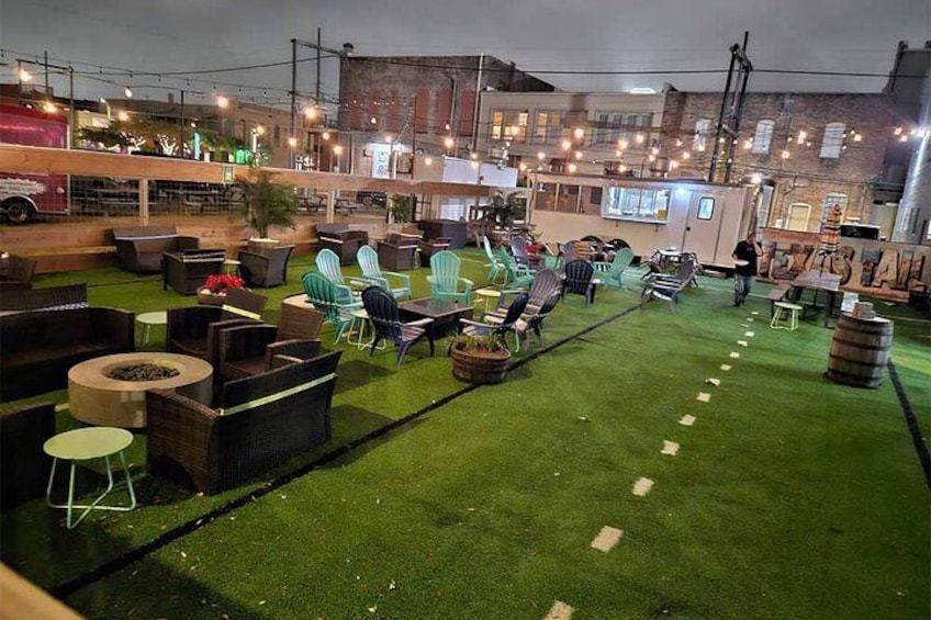 Een terras met kunstgras, rieten meubels en lichtjes. 4