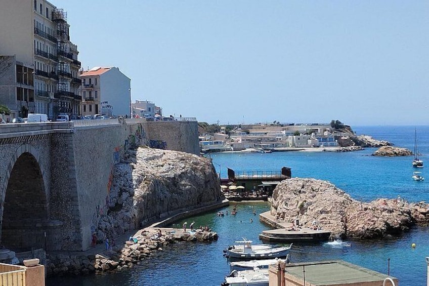A coastal town with a stone bridge, rocky breakwater, and boats in the harbor. 3