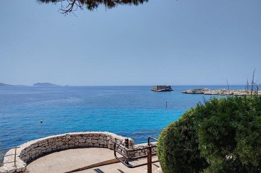 A stone bench overlooking a turquoise sea with distant islands. 2