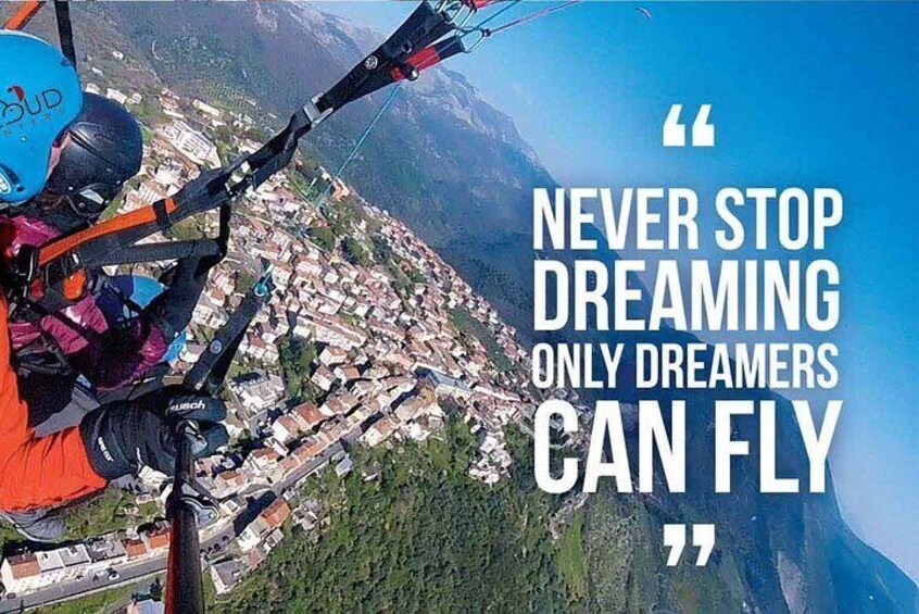 A paraglider flying over a town with a motivational quote. 2