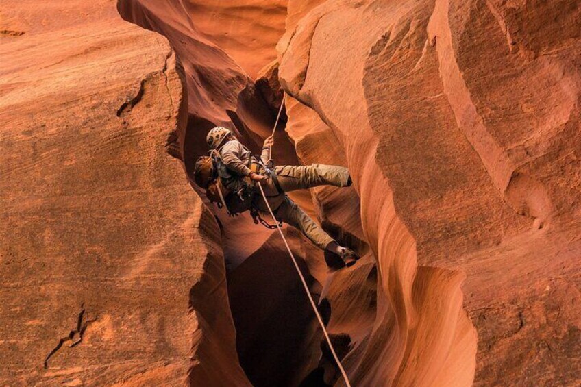 A guest rappelling through a spectacular redrock slot canyon.