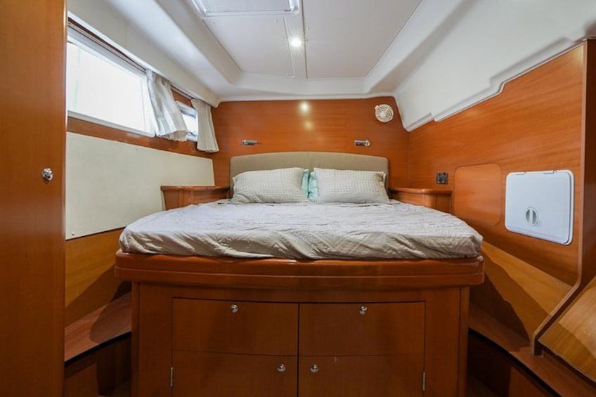A compact, wooden interior with a bed, bedside tables, and a window. 5