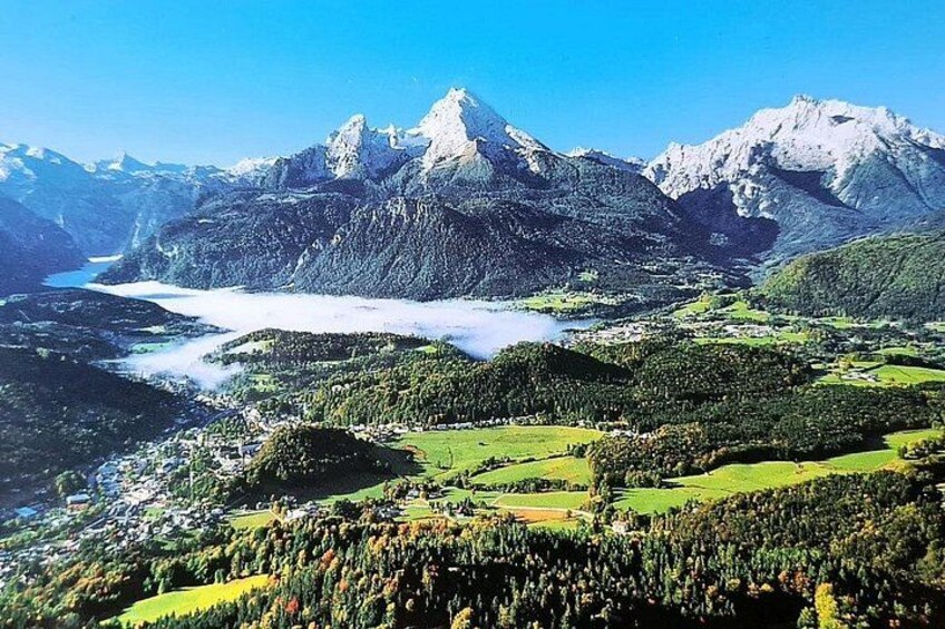 Eine Berglandschaft mit einem See, bewaldeten Gebieten und einer kleinen Siedlung. 2