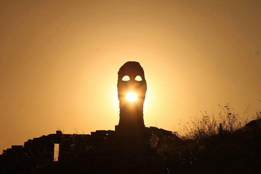 La silhouette d’une structure dotée d’une ouverture circulaire, se détachant sur un coucher de soleil. 1