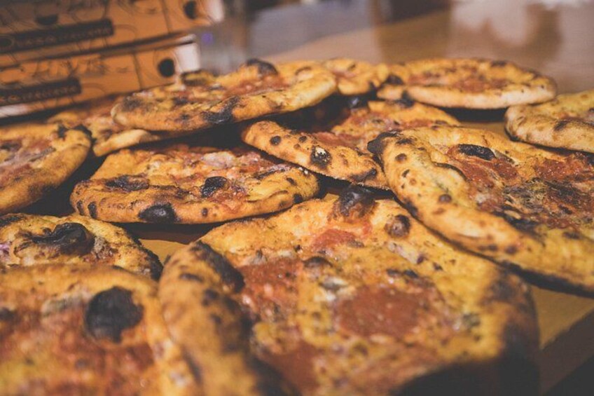 A variety of pizzas with different toppings and charred spots, suggesting they are freshly baked. 3