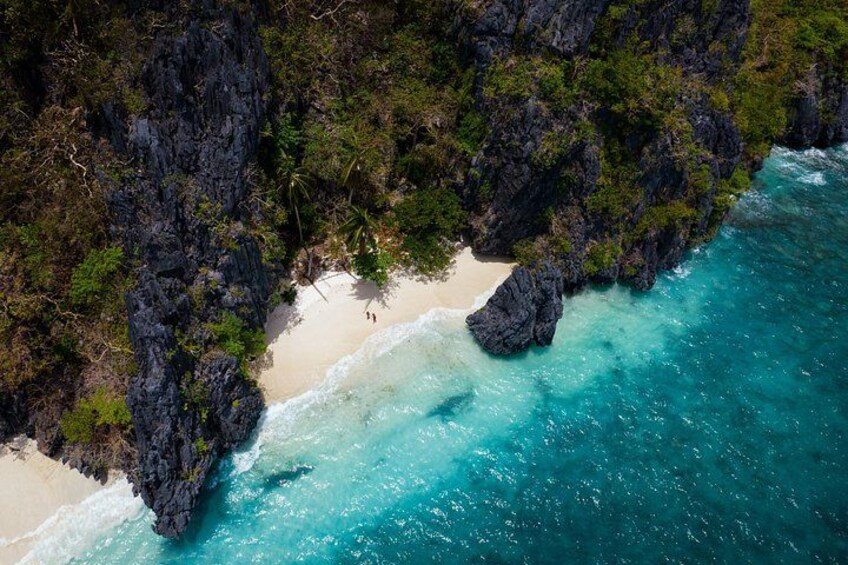 A coastal landscape with a rocky cliff, clear turquoise waters, and a sandy beach. 4