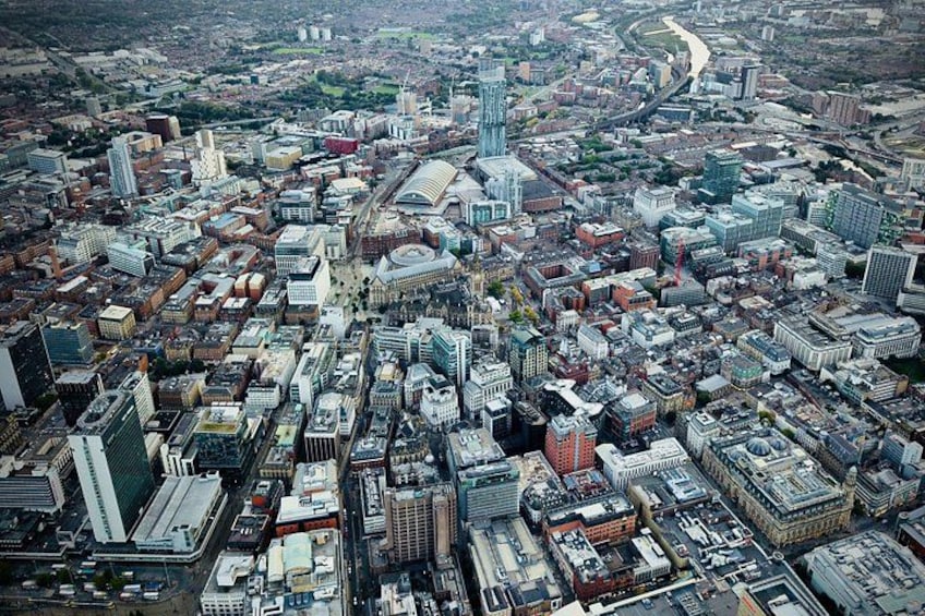 An aerial view of a densely built urban area with numerous high-rise buildings, a river, and a mix of modern and older architecture. 2