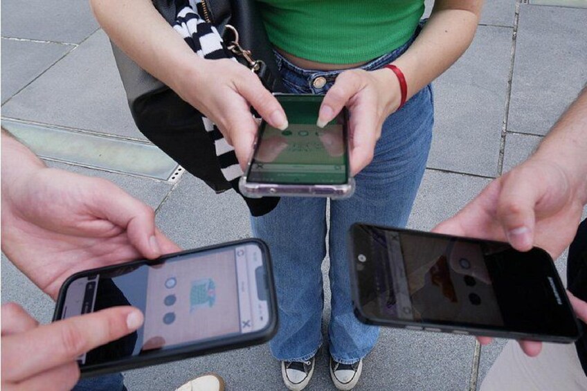 A person holding a smartphone with a green screen, surrounded by other people holding smartphones. 3