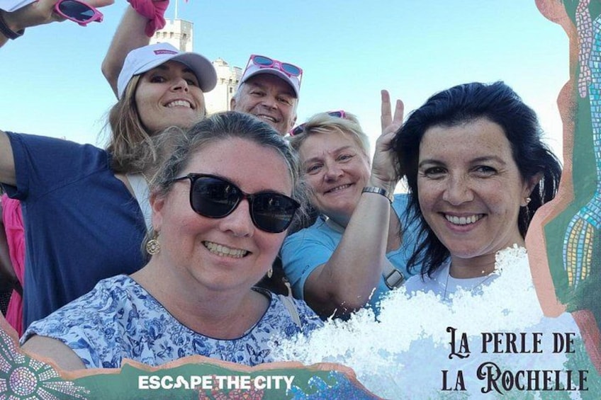 A group of people at an outdoor event with a banner reading 'ESCAPE THE CITY' and 'LA PERLE DE LA ROCHELLE'. 1