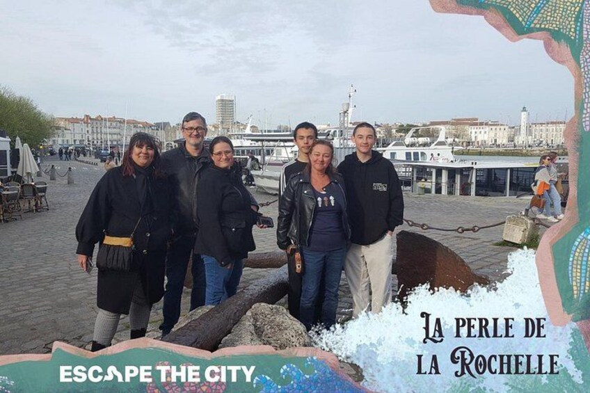 A group of people standing on a waterfront promenade with a cityscape in the background. 2