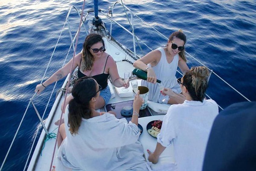 A group of people on a sailboat, with one person pouring a drink. 4