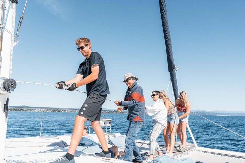 En gruppe mennesker på en sejlbåd, med en klar blå himmel og stille hav i baggrunden. 2