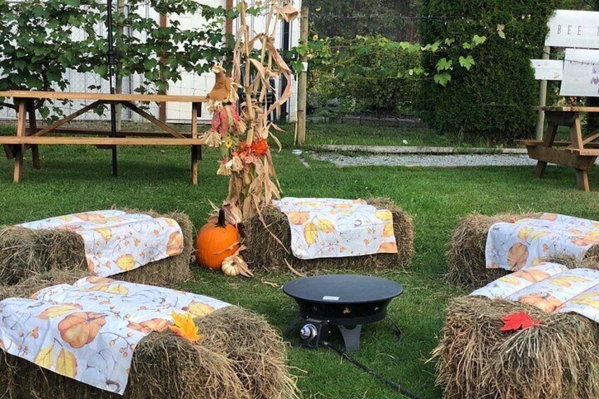 Hay bales with floral tablecloths, a pumpkin, and a rustic outdoor setting. 4