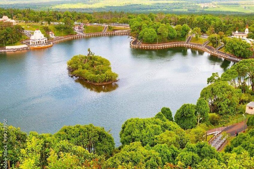 A lake surrounded by lush greenery and a small island with a bridge connecting to the mainland. 5