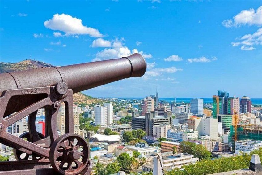 A cannon overlooking a cityscape with modern buildings and a clear sky. 2