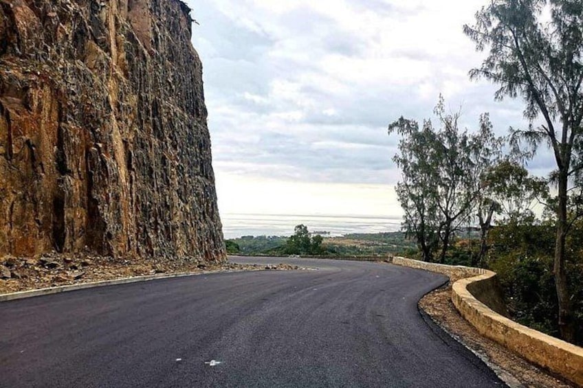 Une route sinueuse, avec une falaise rocheuse sur la gauche et une vue sur l’océan au loin. 2