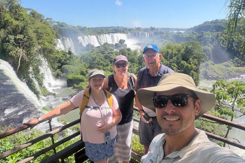 A group of people standing on a bridge overlooking a waterfall. 1
