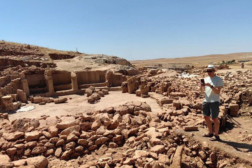 Ancient ruins with stone structures and a person taking a photo. 3