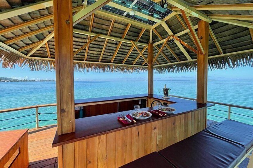 Une terrasse en bois, surmontée d’un toit de chaume, qui offre une vue sur une étendue d’eau. 3