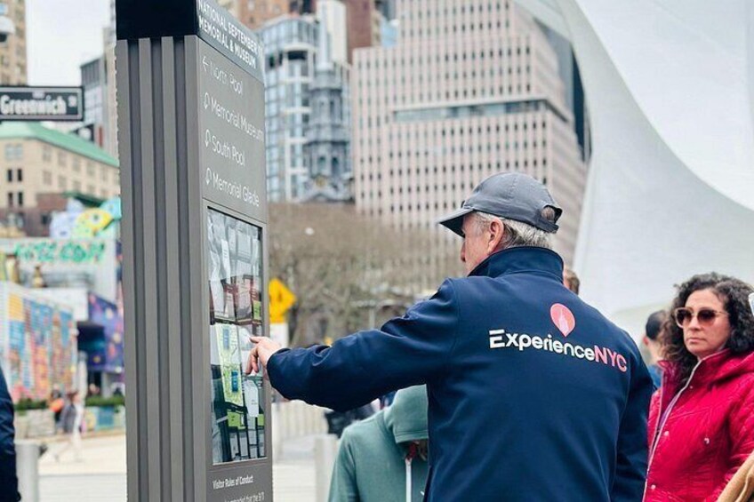 A person using a digital map kiosk in an urban setting with tall buildings in the background. 5