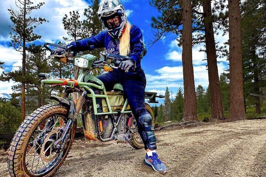 A person riding a dirt bike in a forested area with tall trees. 4