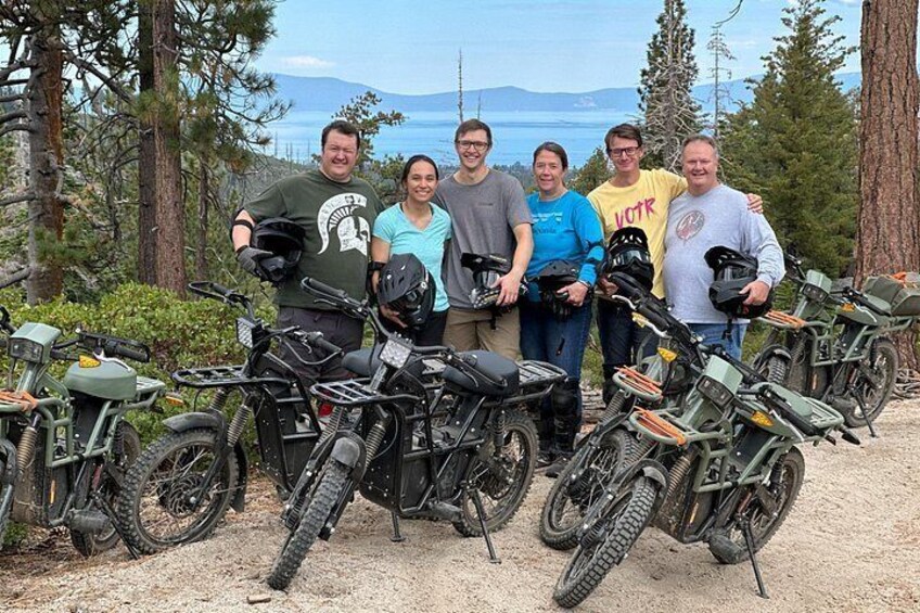 A group of people with ATVs in a forested area with a mountain in the background. 4