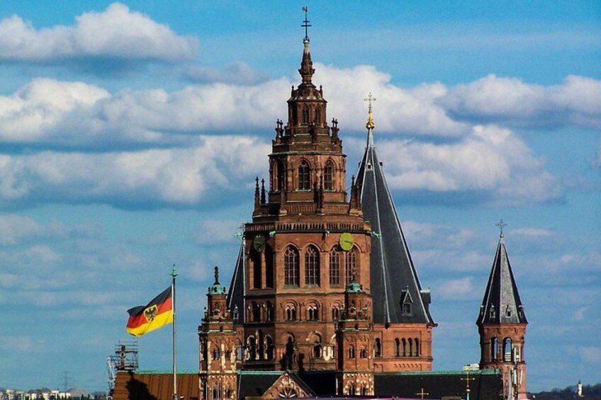 A historic building with a clock tower, a flag, and a clear sky. 2