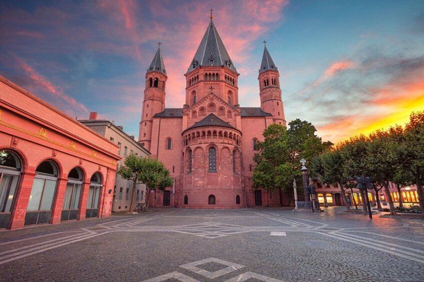 A historic building with two towers, a cobblestone street, and a sunset sky. 1