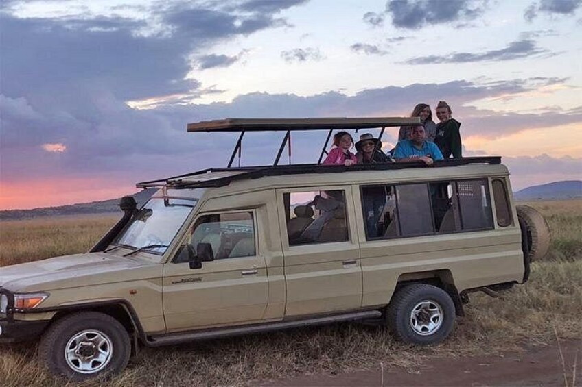 Un vehículo todoterreno color beige con pasajeros circulando por un camino de tierra. 3