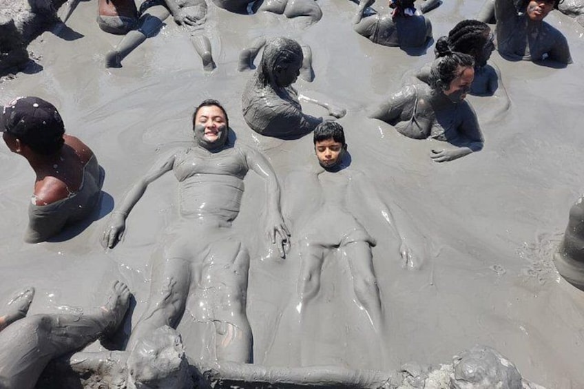 Personas cubiertas con una sustancia gris, probablemente lodo, en un grupo. 1