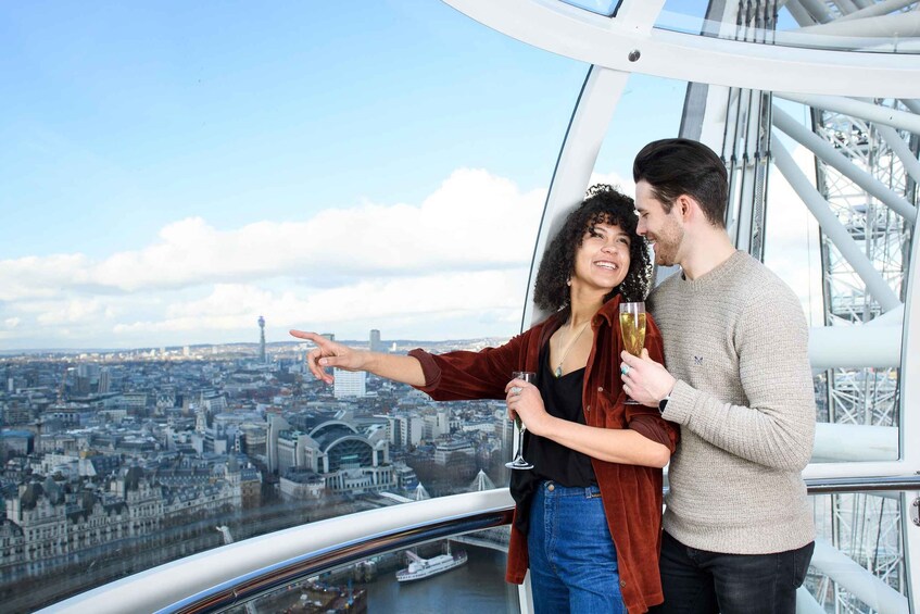 A couple on a glass bridge overlooking a cityscape with a prominent tower and a river. 1