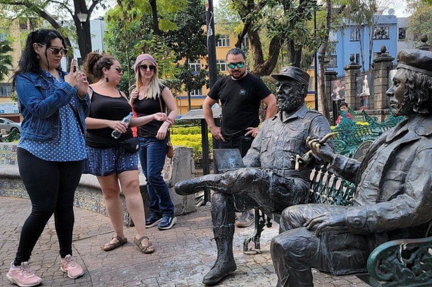 A group of people standing near a statue of a soldier in a park. 3