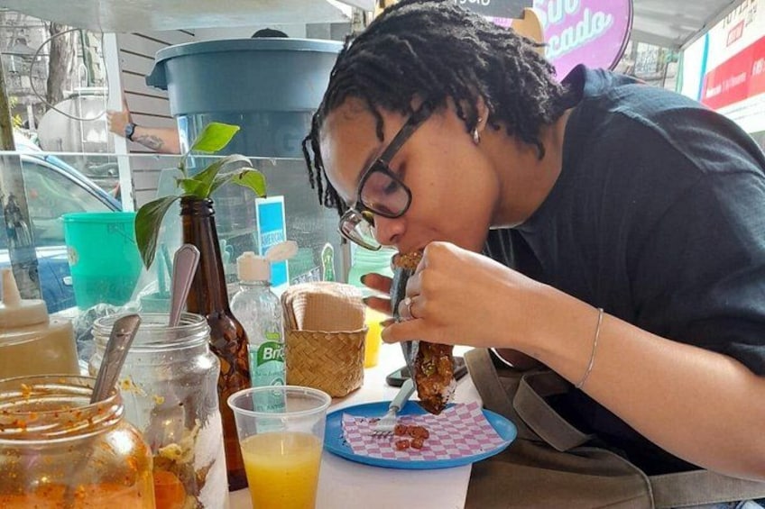 A person eating at a table with various food items and drinks. 5