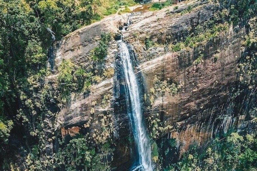 Een waterval stort naar beneden over een rotswand, omringd door weelderige begroeiing. 4