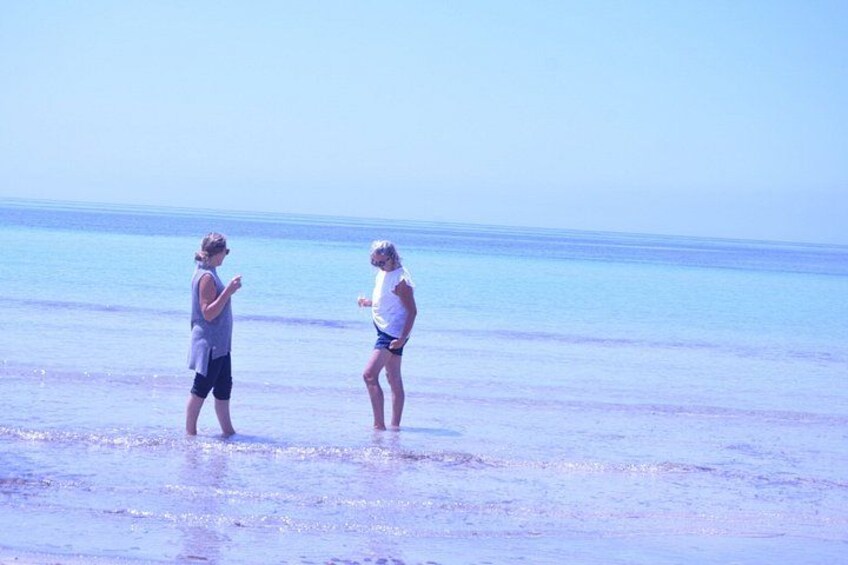 Two people standing on a beach with the ocean in the background. 2