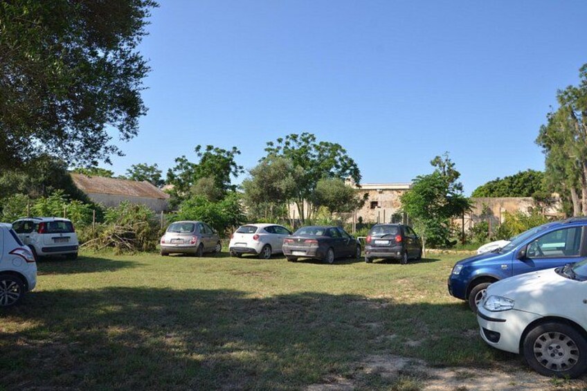 A parking lot with several cars, trees, and a building in the background. 4