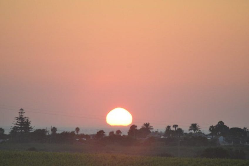 A sunset over a rural landscape with trees and a field. 5