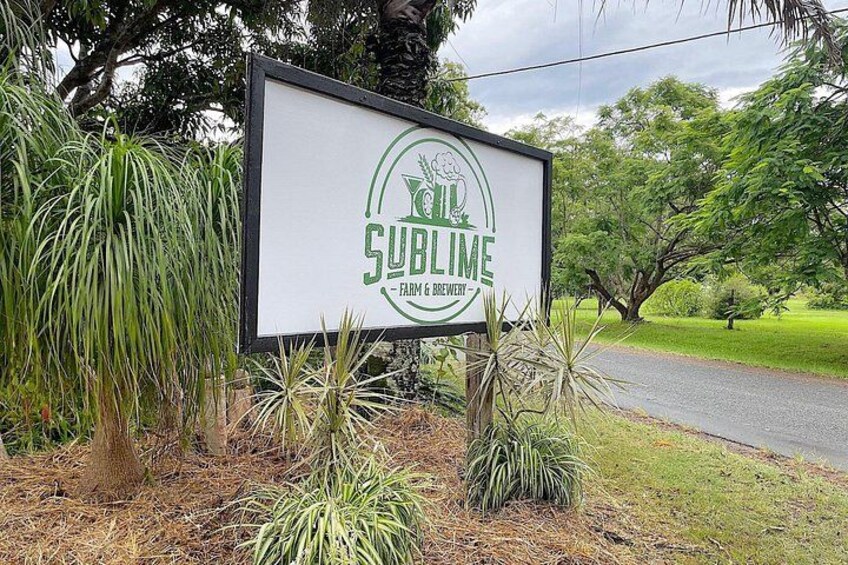 A sign for Sublime Farm & Brewery surrounded by greenery. 5
