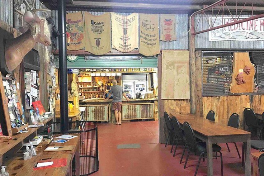 A rustic interior with wooden tables and chairs, a bar area, and various hanging signs. 3