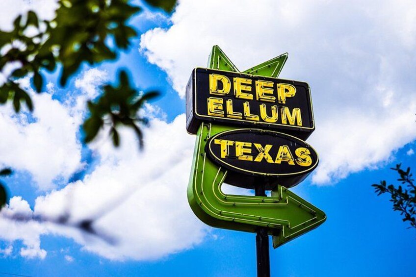 A sign with the words 'DEEP ELLUM TEXAS' against a blue sky with clouds. 2