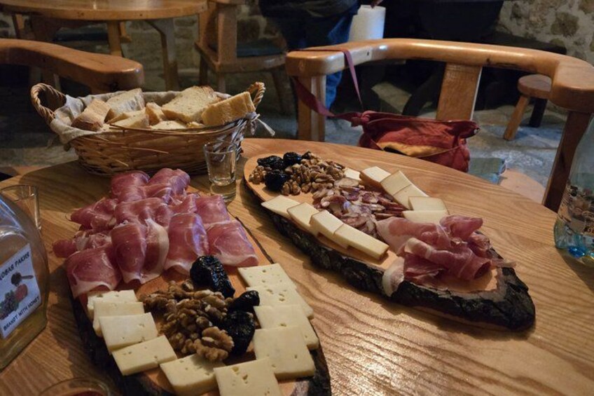 A wooden table with a charcuterie board featuring various cheeses, cured meats, and nuts. 4