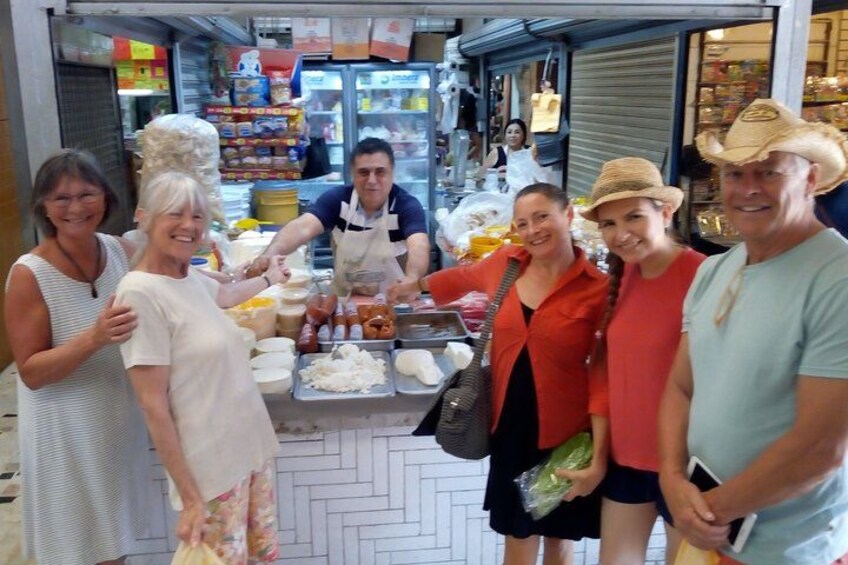 A group of people at a food stall with various food items and condiments. 2