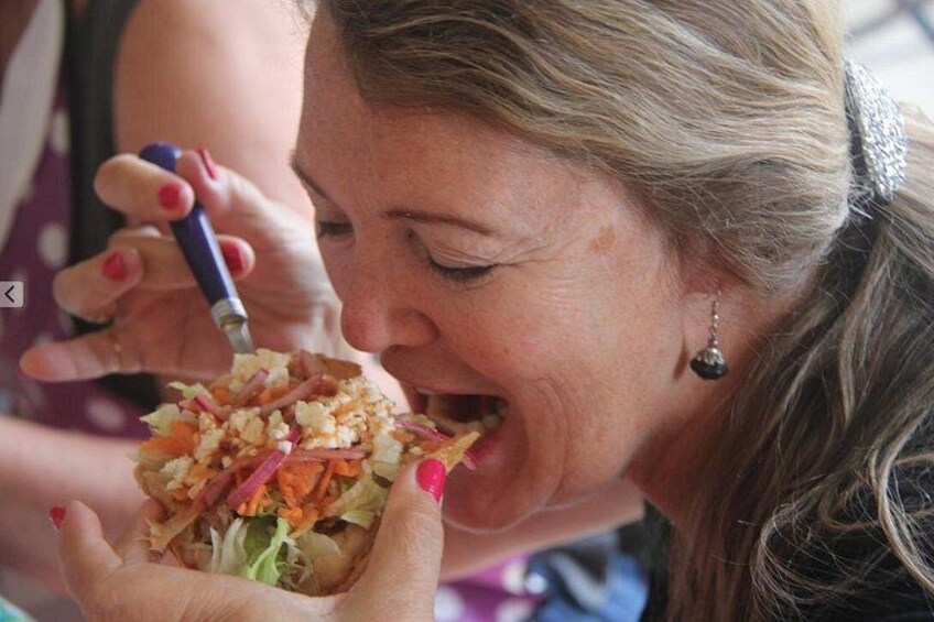 A person holding a sandwich with visible ingredients like lettuce, tomatoes, and possibly meat. 3