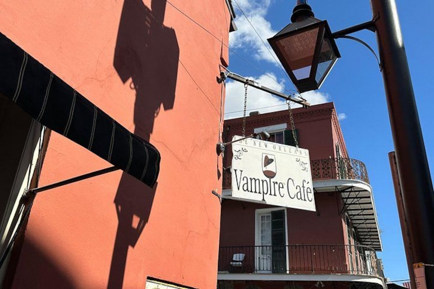 A building with a sign that reads 'Vampire Café' and a street lamp. 2