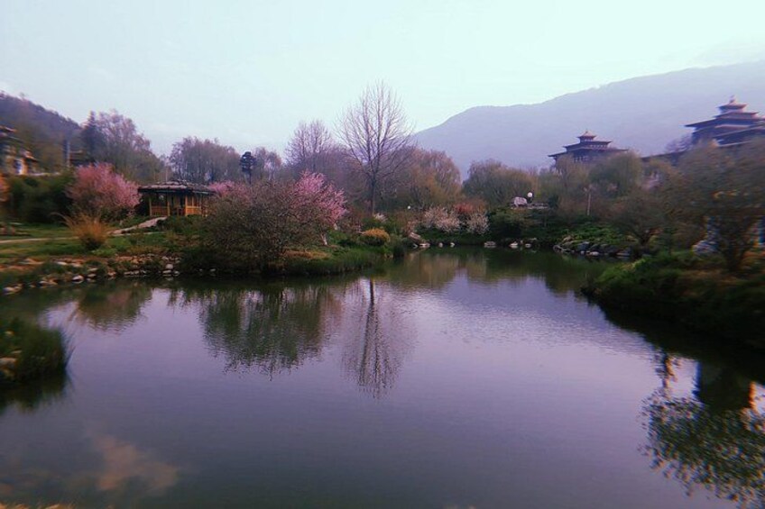 Un lago tranquilo con reflejos, rodeado de árboles y edificios tradicionales. 3