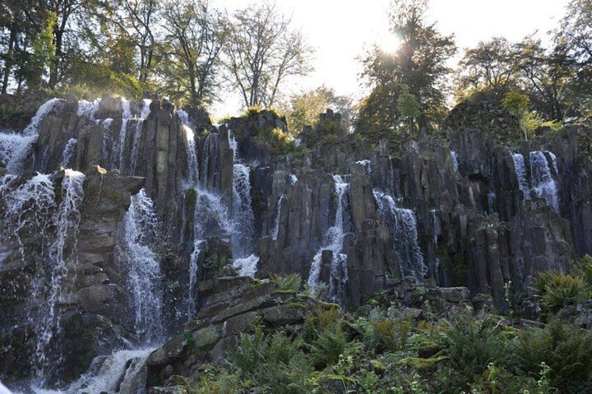 A waterfall cascading over rocky terrain surrounded by lush greenery. 2