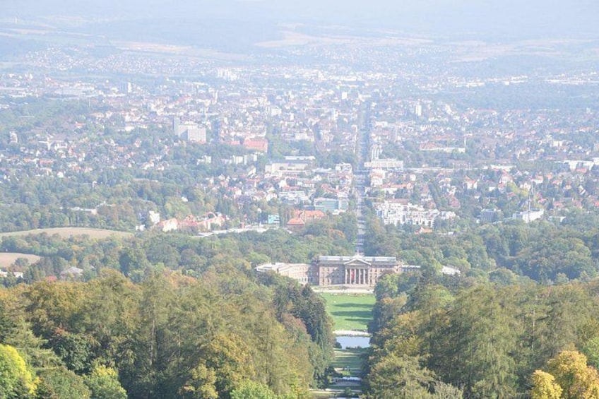 A cityscape with a prominent building in the center, surrounded by greenery and a river. 1